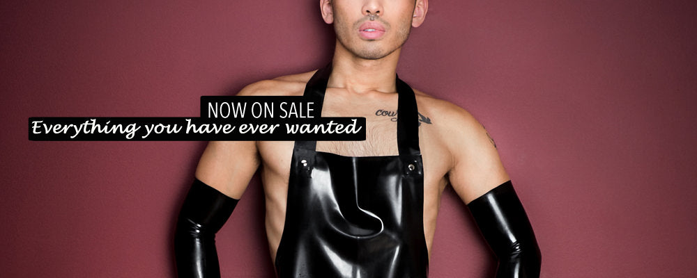 Now on Sale. A man standing up wearing a latex apron and latex elbow gloves.