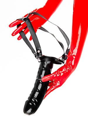 Red latex gloves holding a large strap-on dildo.