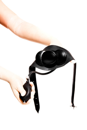 Translucent latex gloves holding an inflatable butterfly gag on a strap.