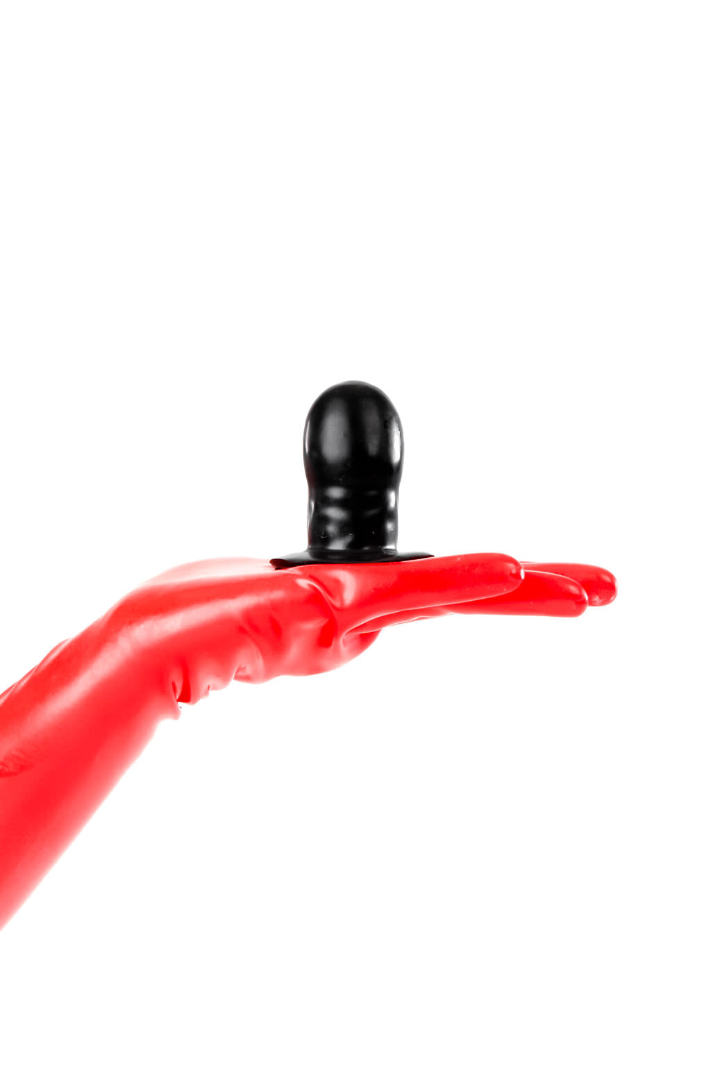 Red latex gloves holding a small solid gag.