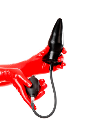 Red latex gloves holding an extra large solid inflatable butt plug.