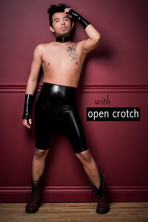 A man wearing crotchless high waisted latex bermuda shorts, black fingerless latex wrist gloves and a latex choker.