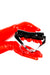 Red latex gloves holding a bit gag. 