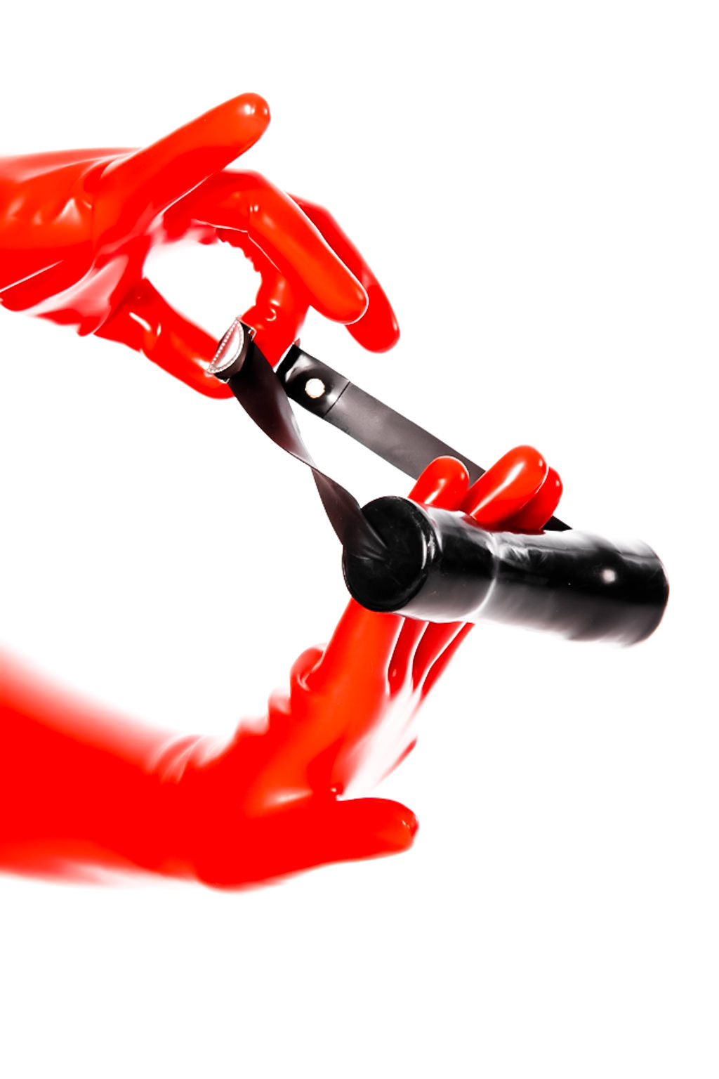 Red latex gloves holding a bit gag. 