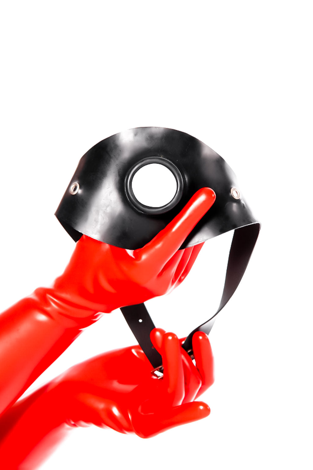 Red latex gloves holding a hollow gag on a strap.