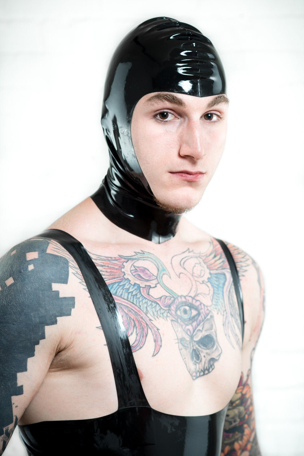 A man wearing a latex leotard and a black latex hood with open face.
