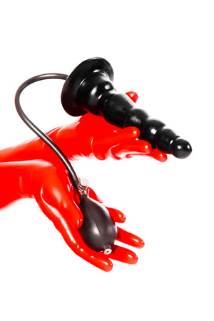 Red latex gloves holding an inflatable ribbed butt plug.
