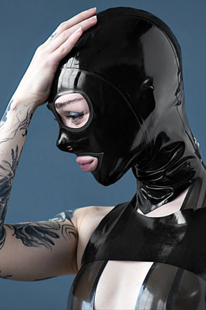 A woman wearing a rubberdoll cat eye latex hood, and a latex top.