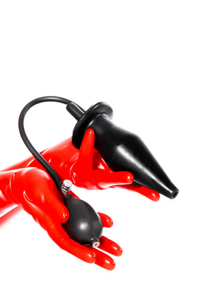 Red latex gloves holding an extra large inflatable enema plug.