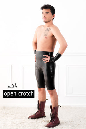 A man wearing a pair of crotchless high waisted latex bermuda shorts and fingerless latex wrist gloves.