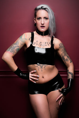 A woman wearing a latex outfit with a black latex camisole top.
