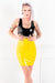 A woman wearing a black latex crop top and a yellow latex mini skirt.