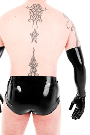 A man wearing black latex shoulder gloves and latex underwear. A rear view, showing his ass.