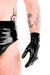 A man wearing a pair of latex wrist gloves and black latex briefs.